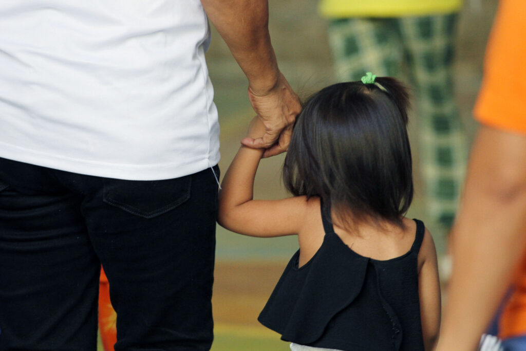 Father and child holding hands while walking